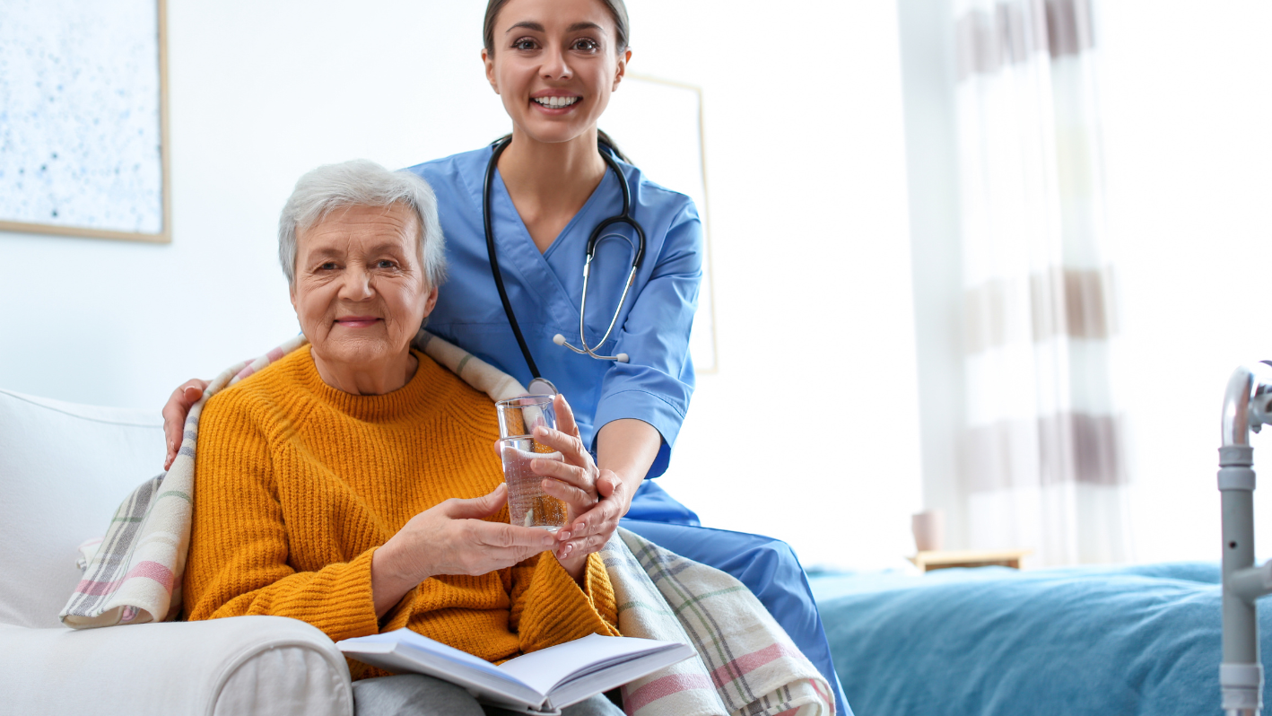 A nurse holding a glass of water next to an elderly woman